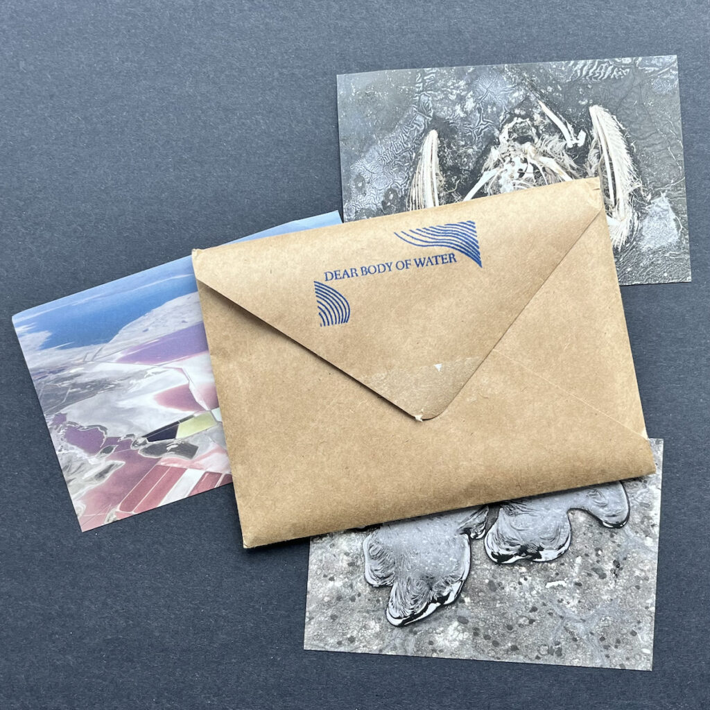 An envelope with a stamp on the back "Dear Body of Water" beneath the envelope are three partially obscured postcards