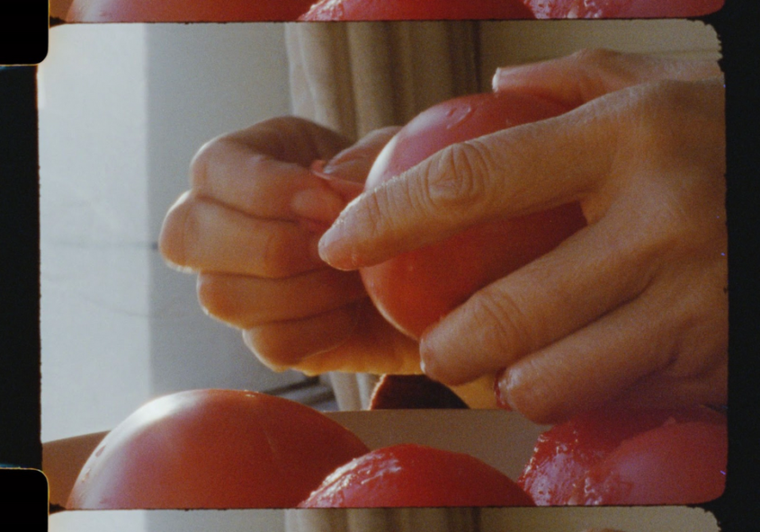 digitized still of filmic images. hands holding what might be a peach.